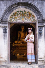 A young Thai woman dressed in traditional Northern Thailand culture costume visits a temple in Chiang Mai, Thailand.