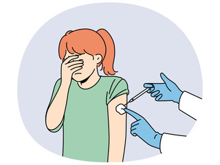 Crying little girl is afraid of injections and closes eyes during injection in shoulder and vaccination against measles or flu. Hands of doctor with syringe making injection to child