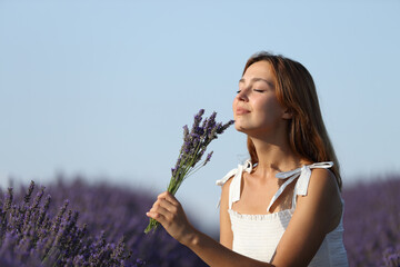Woman smelling lavender flowers in a sunny field