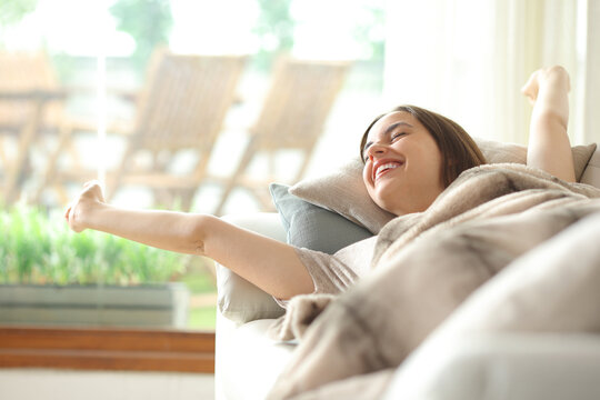 Happy woman waking up stretching arms from a nap
