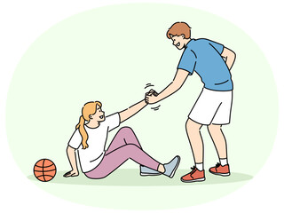 Basketball caviar helps fallen girl to stand up, showing team solidarity with injured opponent. Responsive friend lending helping hand to friend sitting on ground near basketball ball
