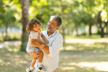 Happy father holding laughing son in the air at park