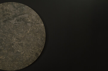 Top view of brown marble plate on black background. Food presentation, stone tray. Copy space, flat lay.