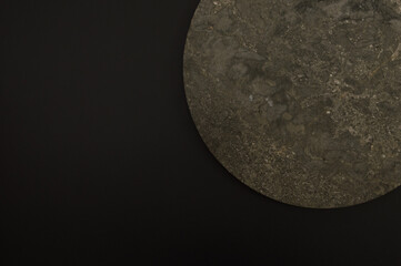 Top view of brown marble plate on black background. Food presentation, stone tray. Copy space, flat lay.