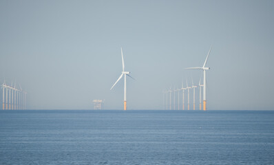 many tall wind turbines of an offshore wind farm, in action, Gwynt y Môr (Sea wind) 576-megawatt offshore wind farm with 160 x 150m high turbines in Colwyn Bay Wales