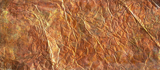Crumpled copper foil reflects light, revealing its irregular surface texture