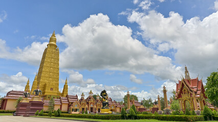 Panoramic view of stunning exterior architecture in buddhist temple with golden pagoda under cloudy blue sky. Wat Mahathat Wachiramongkhon or Wat Bang Thong, Krabi Province, Thailand.