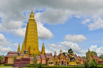 Beautiful scenery of a great golden pagoda in buddhist monastery under cloudy blue sky. Wat Mahathat Wachiramongkhon or Wat Bang Thong, Krabi Province, Thailand. 