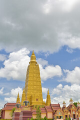 Vertical stunning photograph of a great golden pagoda in buddhist monastery under cloudy blue sky. Wat Mahathat Wachiramongkhon or Wat Bang Thong, Krabi Province, Thailand.