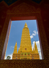 Stunning great golden pagoda with blue sky in buddhist temple. Photo shot through the window. Wat Mahathat Wachiramongkhon or Wat Bang Thong, Krabi Province, Thailand. 