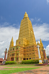 Wat Mahathat Wachiramongkhon or Wat Bang Thong, Krabi Province, Thailand. Stunning huge golden pagoda in buddhist temple under cloudy blue sky during summer.