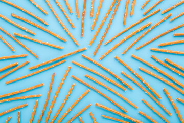 Long thin dry cracker sticks on light blue table background. Pastel color. Closeup. Salty snack...