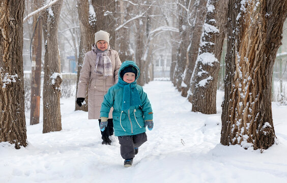 Cute boy walking with grandmother on snow at winter