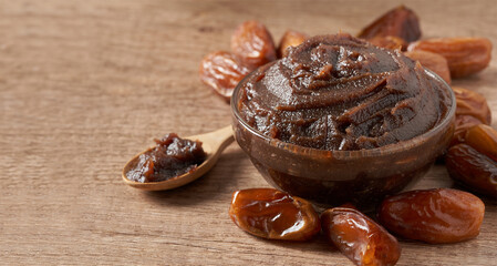 closeup pile of dry date palm fruit and date spread jam in glass bowl on food background with copy...
