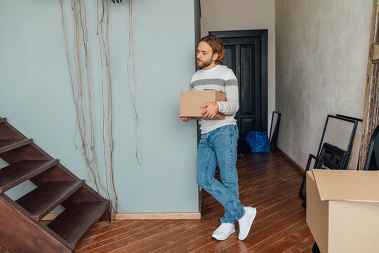 Young man holding cardboard box leaning on wall