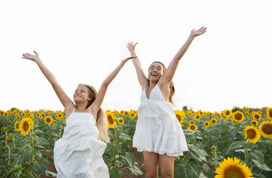 Sisters in white dress enjoying leisure time in sunflower field