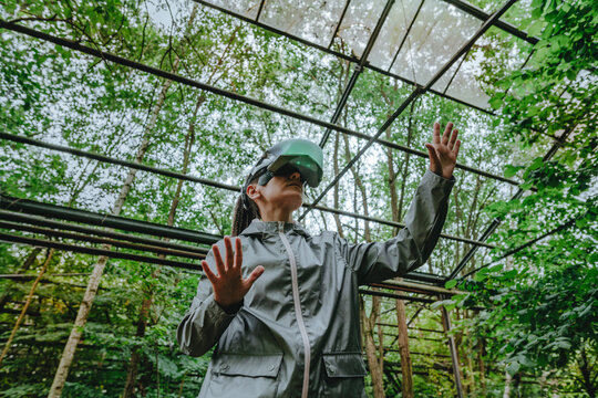 Woman with VR glasses gesturing in greenhouse