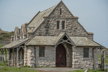 Great Orme Cemetery Chapel, Llandudno, a pretty stone-built medieval church standing amongst many grave stones in a cemetery