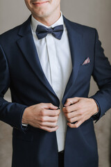 A man in a suit and tie is wearing a blue jacket and white shirt. He is adjusting his tie and holding his hands in his pockets. Concept of formality and professionalism