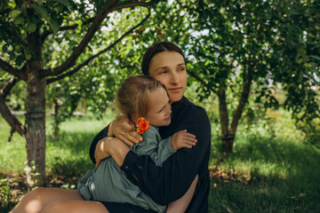 Mother and daughter family in a summer green garden together, happy and hugging
