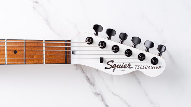 Samara, Russia - October 8, 2023: Squier Telecaster headstock on marble background. White electric guitar headstock on white marble background. Wood neck, white headstock with black pegs.