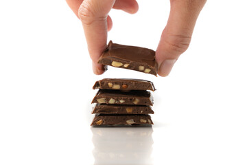 hand stacking chocolate bar with cashew nuts, isolated on white background