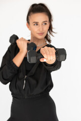 Young girl posing with dumbbells for power training, indoors. athlete wearing black leggings and shirt