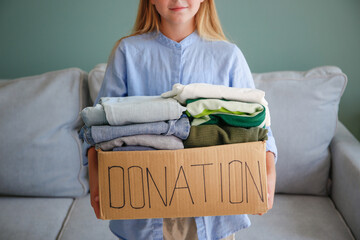Girl holding donation box with with clothes.