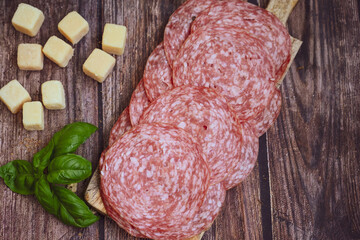 Slices Of  Traditional Italian antipasti salame Milano, parmesan cheese   on a wooden  cutting board.