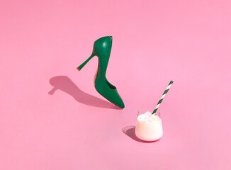 Women's green shoe and cold white cocktail. High heel shoe on sunny day, refreshing drink and pink background.