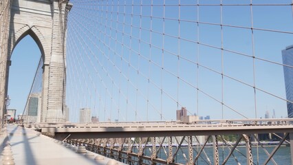 Fototapeta premium Brooklyn Bridge to Manhattan, cables, blue sky. New York City iconic symbol, USA travel destination. Architecture of United States of America, tourist landmark. Famous cable-stayed bridge screw bolts.