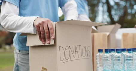 Volunteer, people and hands with donation box in park for social responsibility, outreach and charity. Packing, team and cardboard with food drive for community service, support and NGO project