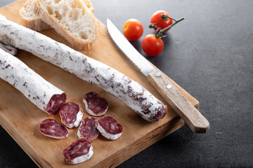 Fuet.Dry cured fuet sausage on black slate background. Copy space