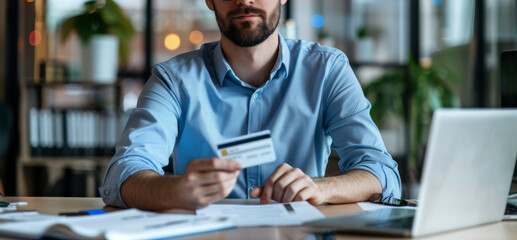 Obraz premium business man holding a credit card and mobile phone in an office, 