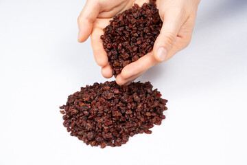 A handful of dried red barberries on a white background.