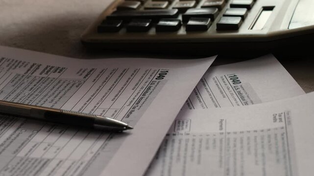 concept calculation and payment of taxes of a US citizen, tax form 1040 on the table, pen and hand counting on a push-button calculator, tax deductions filling out a declaration