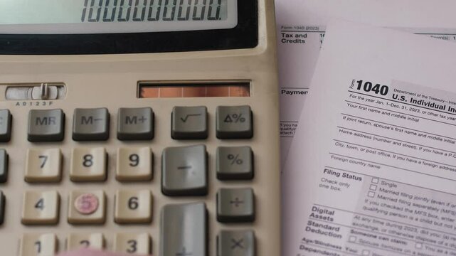 concept of paying taxes on income, push button calculator and tax returns 1040 forms, budgeting, expenses and taxes planning