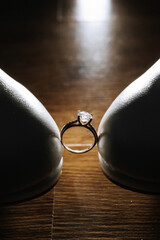 A ring is placed on a pair of shoes, with the ring being the main focus of the image. The shoes are...