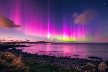 The night sky near a peaceful ocean is illuminated by the vibrant and colorful display of the aurora borealis, creating a stunning natural phenomenon and serene landscape.