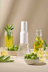 Front view of white bottle unlabeled surrounded by glass bottles and bowl fill with fresh olives and olive oil. Mockup for cosmetic of lemon extract. Advertising photo