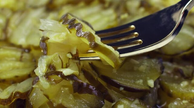 Green homemade pickled fermented cucumbers. Slices of marinated cucumber salad taking by a fork close up