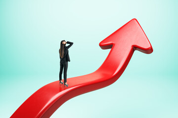 Obraz premium Young businesswoman standing on upward red arrow. Blue background. Growth and success concept.