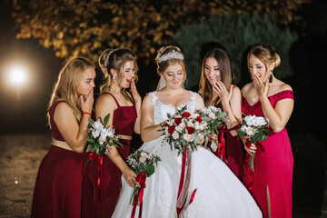A bride and her five bridesmaids are posing for a picture. The bride is wearing a white dress and a...