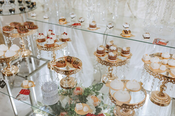 A table with a variety of desserts, including cakes and cupcakes, is displayed in a glass case. The desserts are arranged in a way that makes them look appealing and tempting