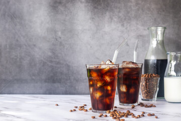 iced homemade cold brew coffee  with glass straw on white marble  table.