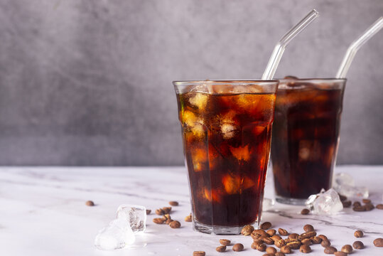 iced homemade cold brew coffee  with glass straw on white marble  table.