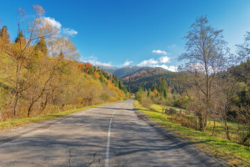 asphalt road through autumn landscape mountains. beautiful and colorful scenery on sunny day under the blue sky with some clouds. country road in ukraine