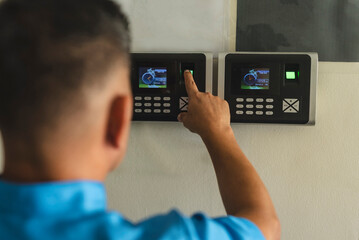 A janitor or clerk clocking in on a fingerprint biometric scanner. Recording attendance times of...