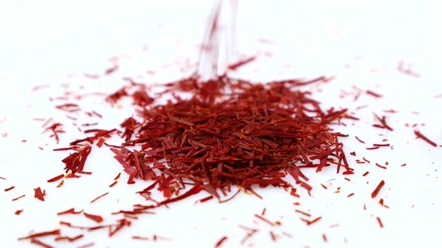 Bright red cut saffron pistils falling down on white background close up