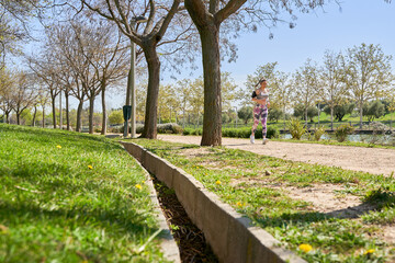 full view of a woman jogging in a park with copy space for text